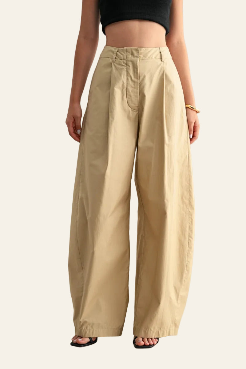 Person wearing beige wide-leg pants on a plain background