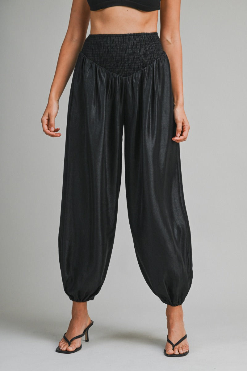 Black high-waisted pants worn by a person on a gray background
