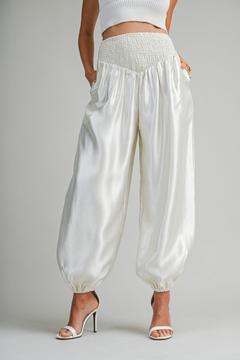 White satin harem pants worn by a person on a plain background