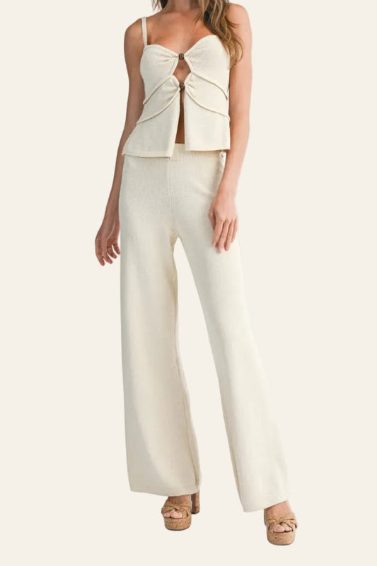 Woman wearing a cream-colored outfit with a top and wide-leg pants on a white background