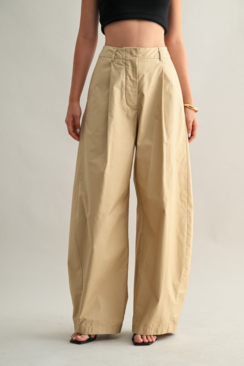 Person wearing beige wide-leg pants on a plain background