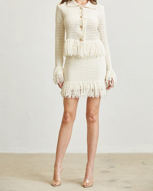 White textured outfit with fringe details on a plain background