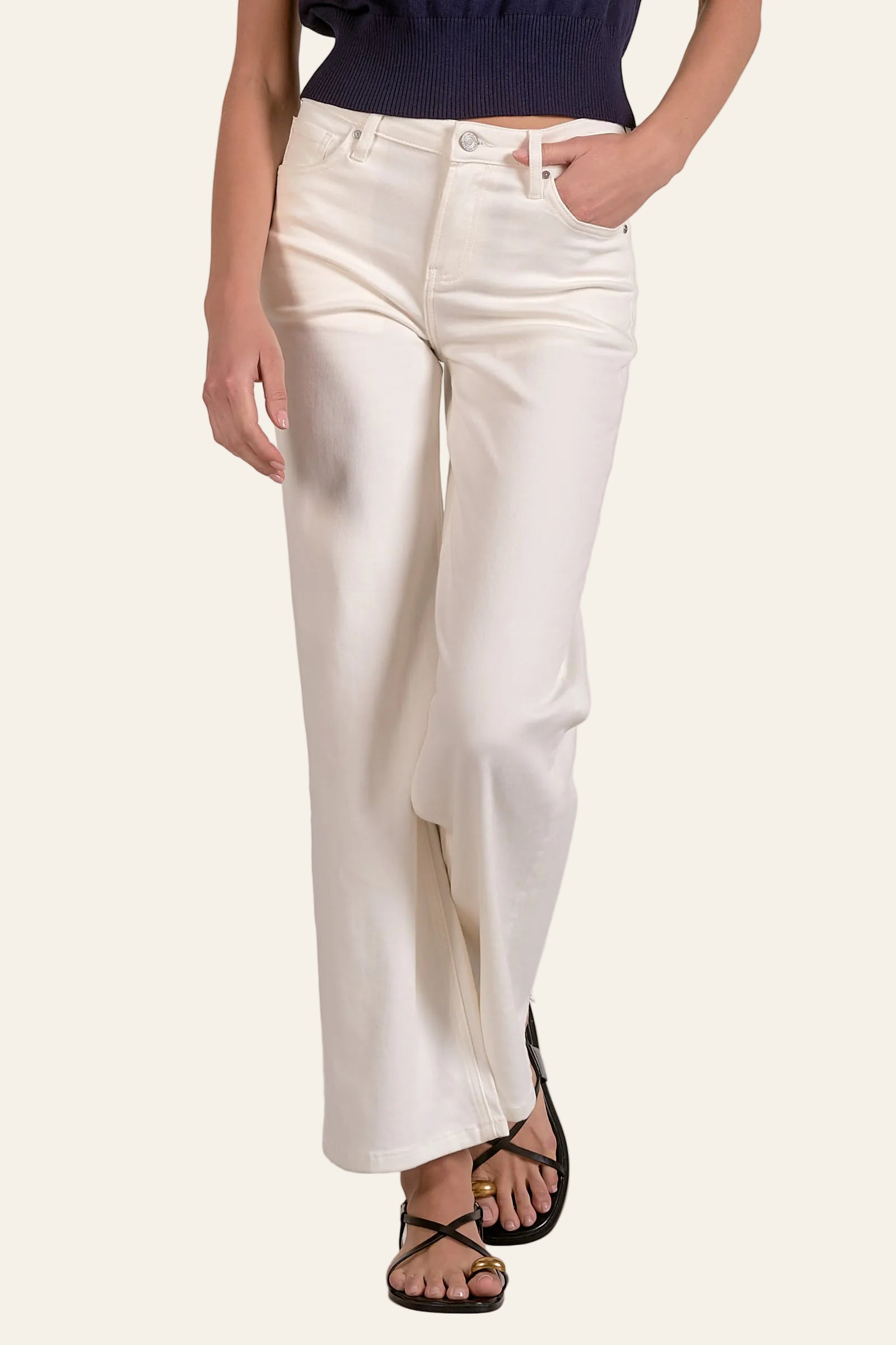 Person wearing white pants and a navy top on a plain background
