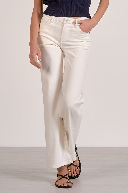 Person wearing white pants and a navy top on a plain background