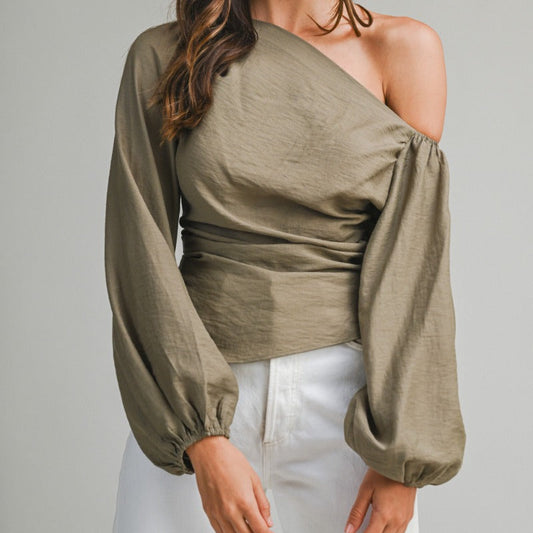 Woman wearing a green one-shoulder top with long sleeves on a plain background