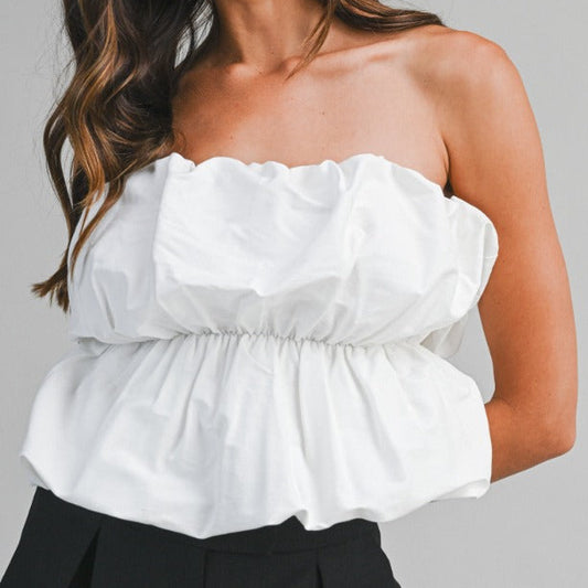 White off-shoulder top worn by a person on a gray background